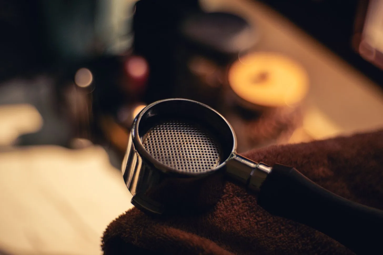 An empty espresso portafilter resting on a dark cloth